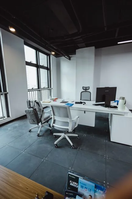 A tidy home office space featuring a wooden desk, chair, broom, and cleaning equipment.